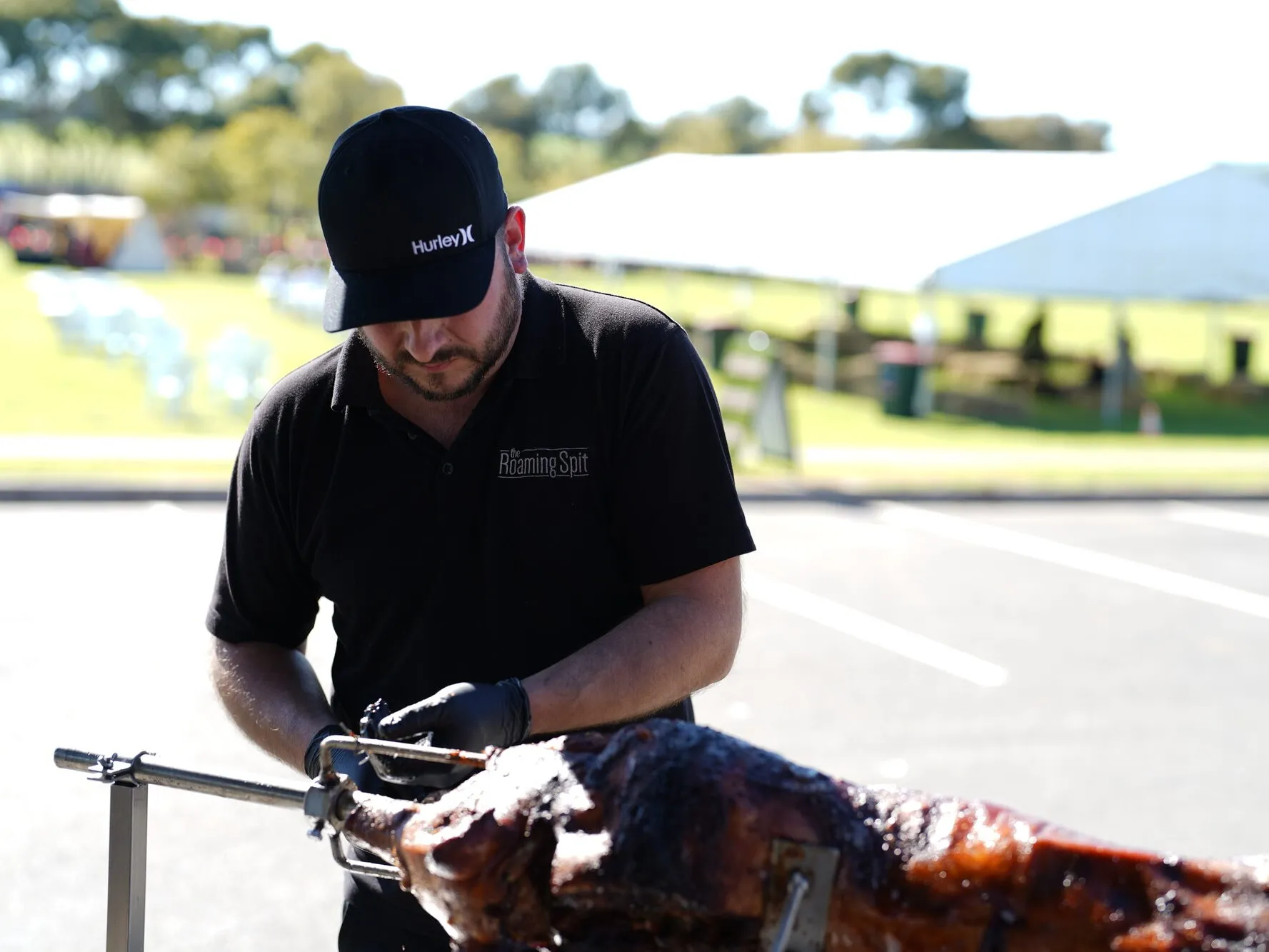 Ivan tending the spit roast at an outdoor event surrounded by guests